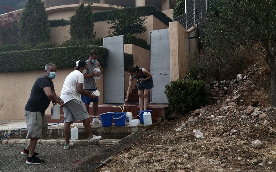 Kάτοικοι και απλοί εθελοντές προσπαθούν να σβήσουν τις φλόγες με κουβάδες και λάστιχα.